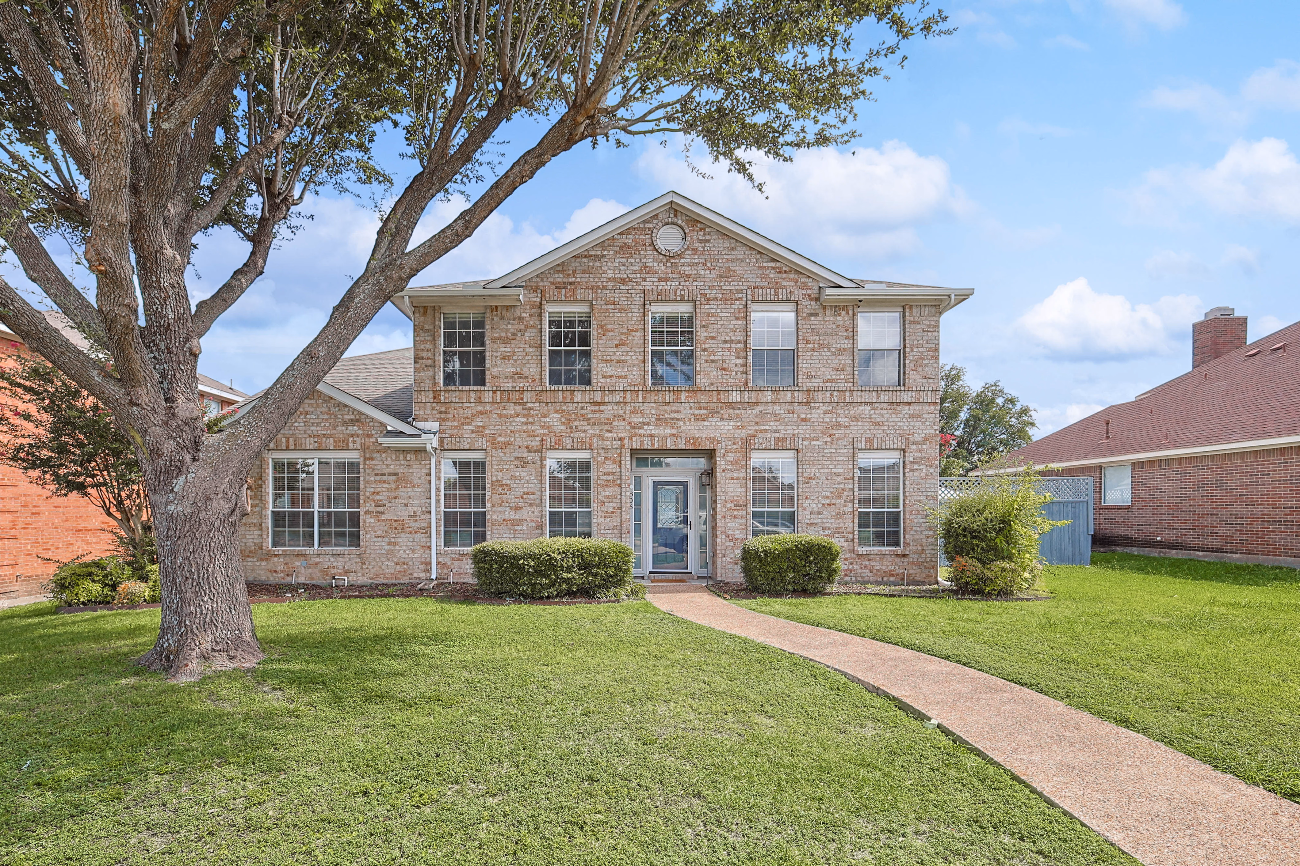 Front of house from the street — symmetrical brick exterior and manicured lawn.