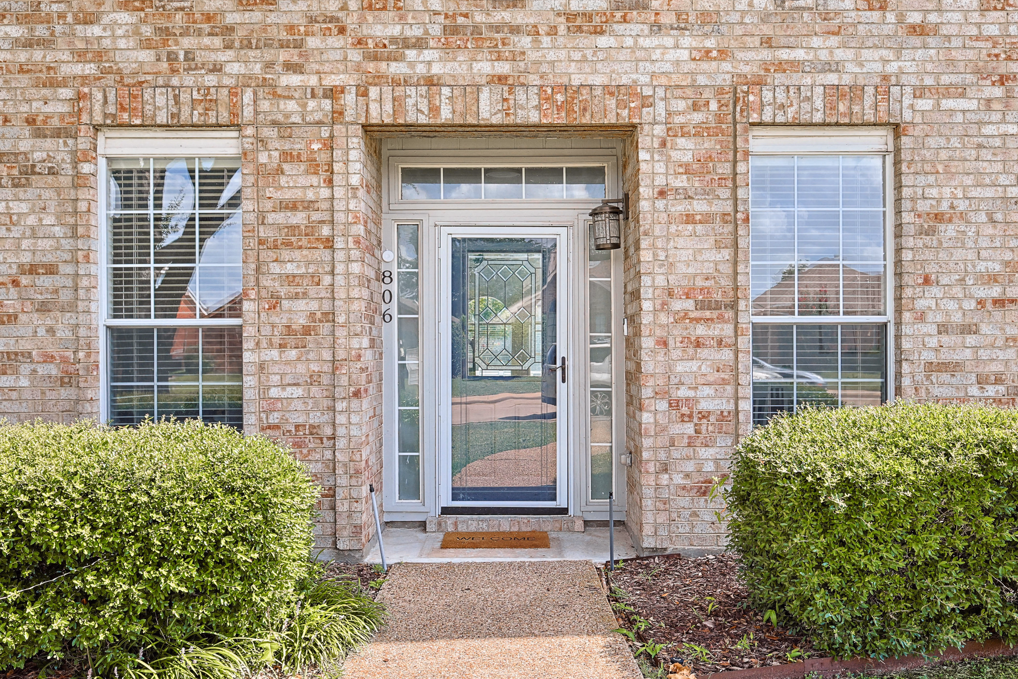 Front entry detail — leaded-glass door, 806 address plate, brick surround.