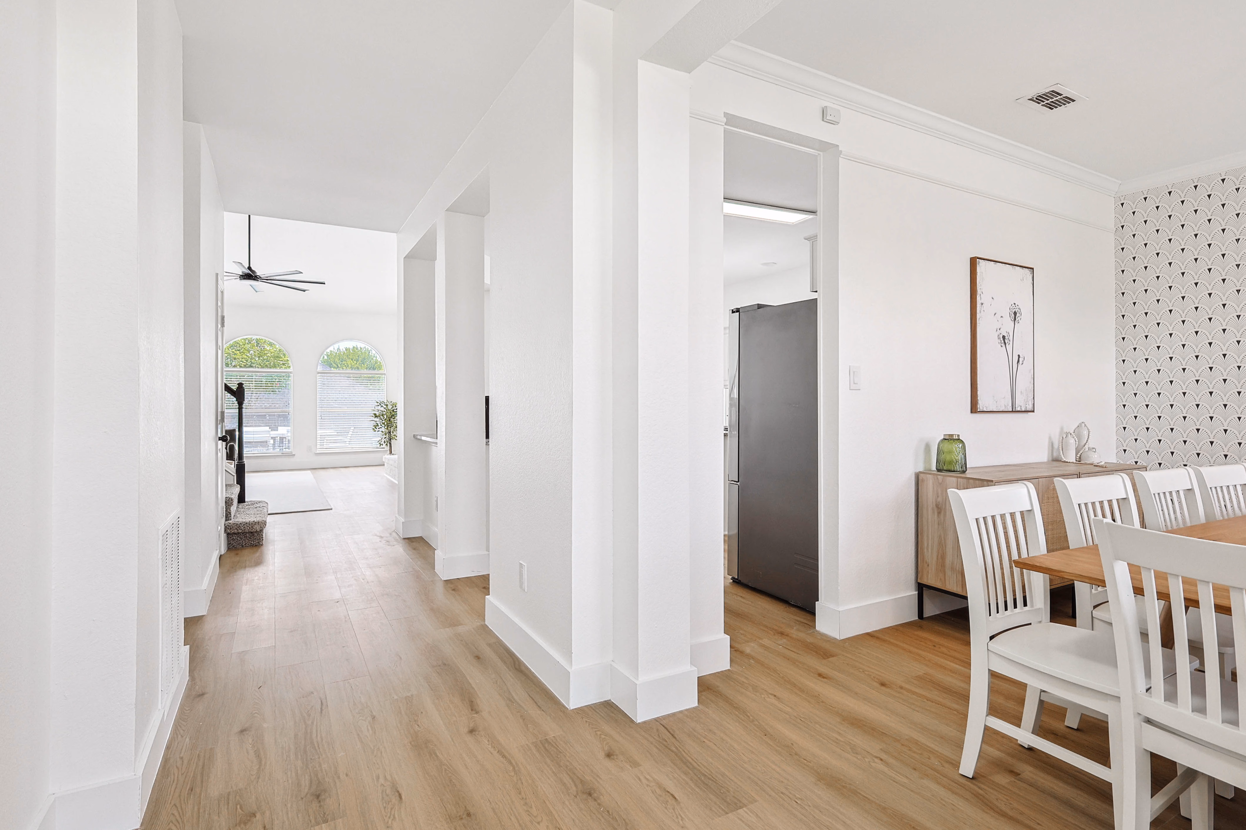 Great room — white sectional and ladder shelf under vaulted ceiling, arched windows looking out to pool.
