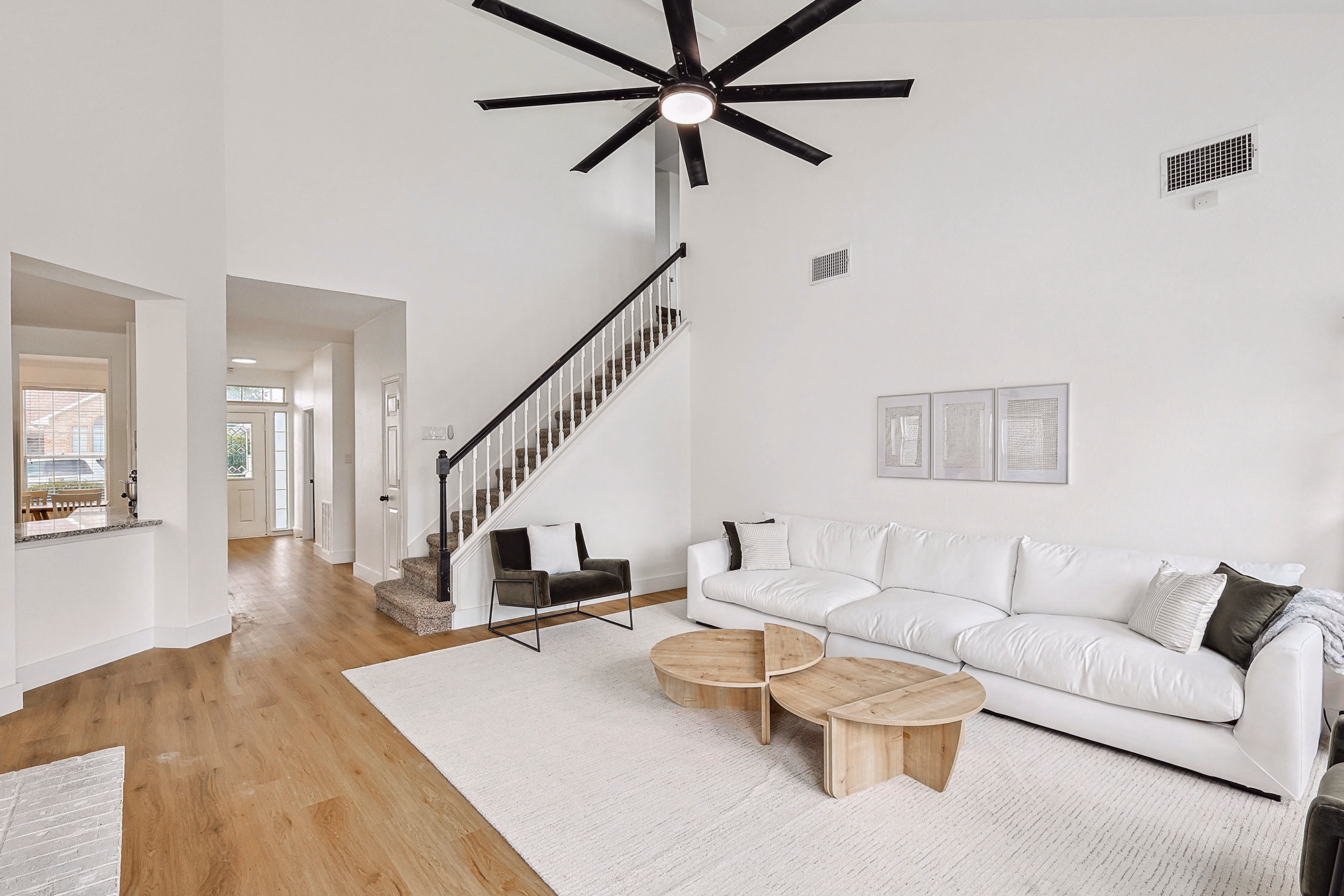 Great room — wall-mounted Roku TV above white brick fireplace, sightline through to kitchen and stairs.