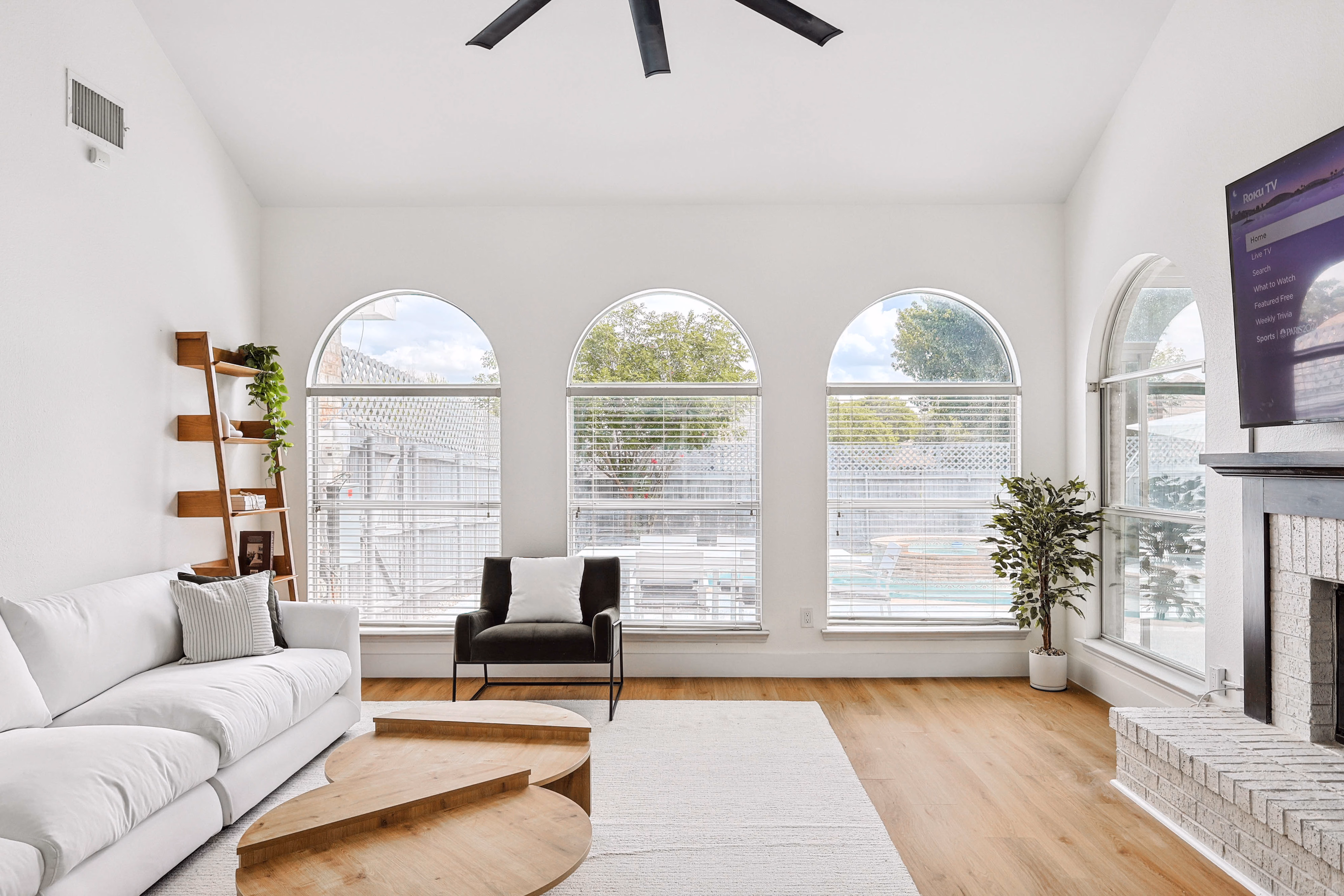Great room — TV above fireplace, arched windows along the back wall.