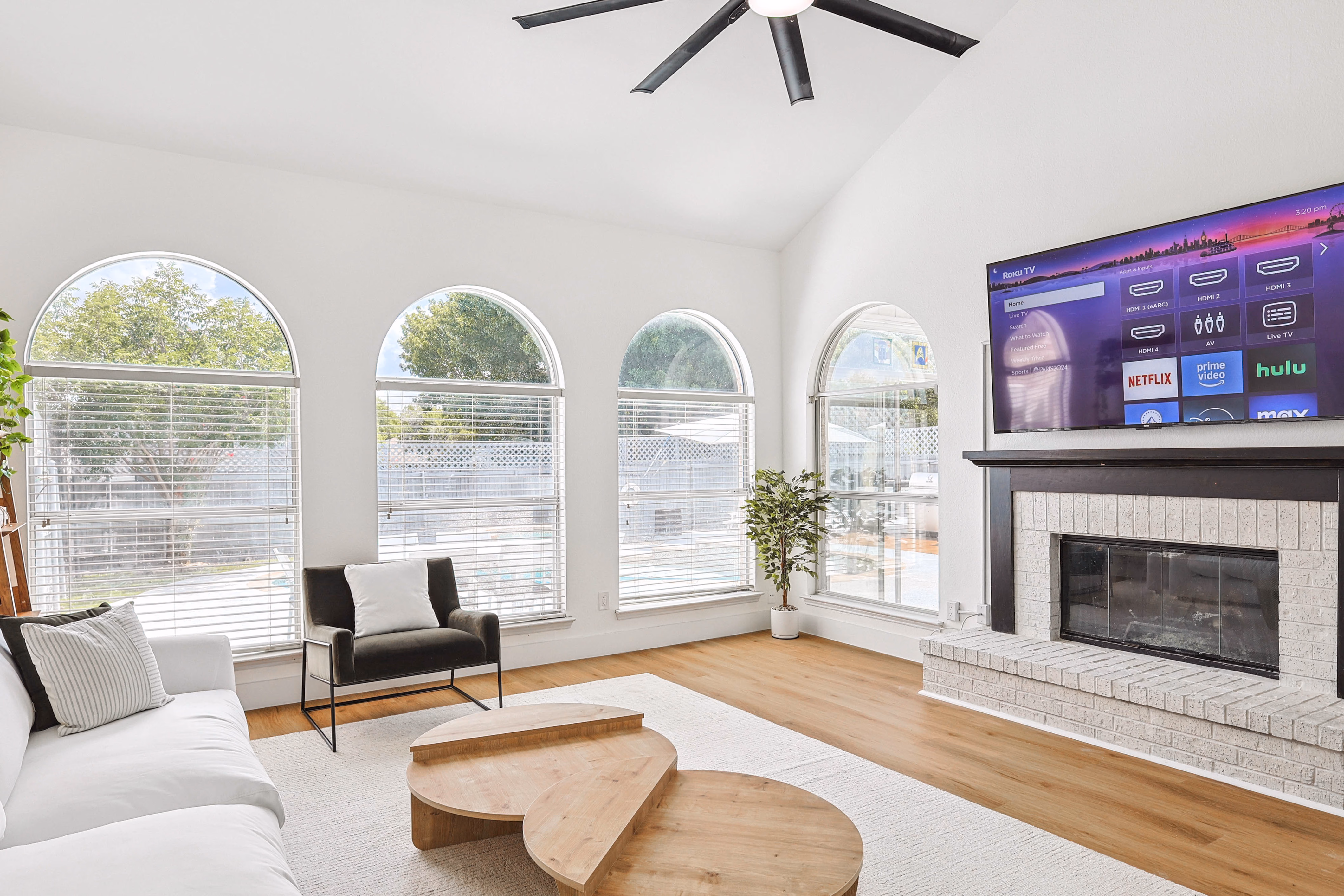 Great room — full vaulted ceiling, oversized industrial fan, fireplace and back-wall windows.