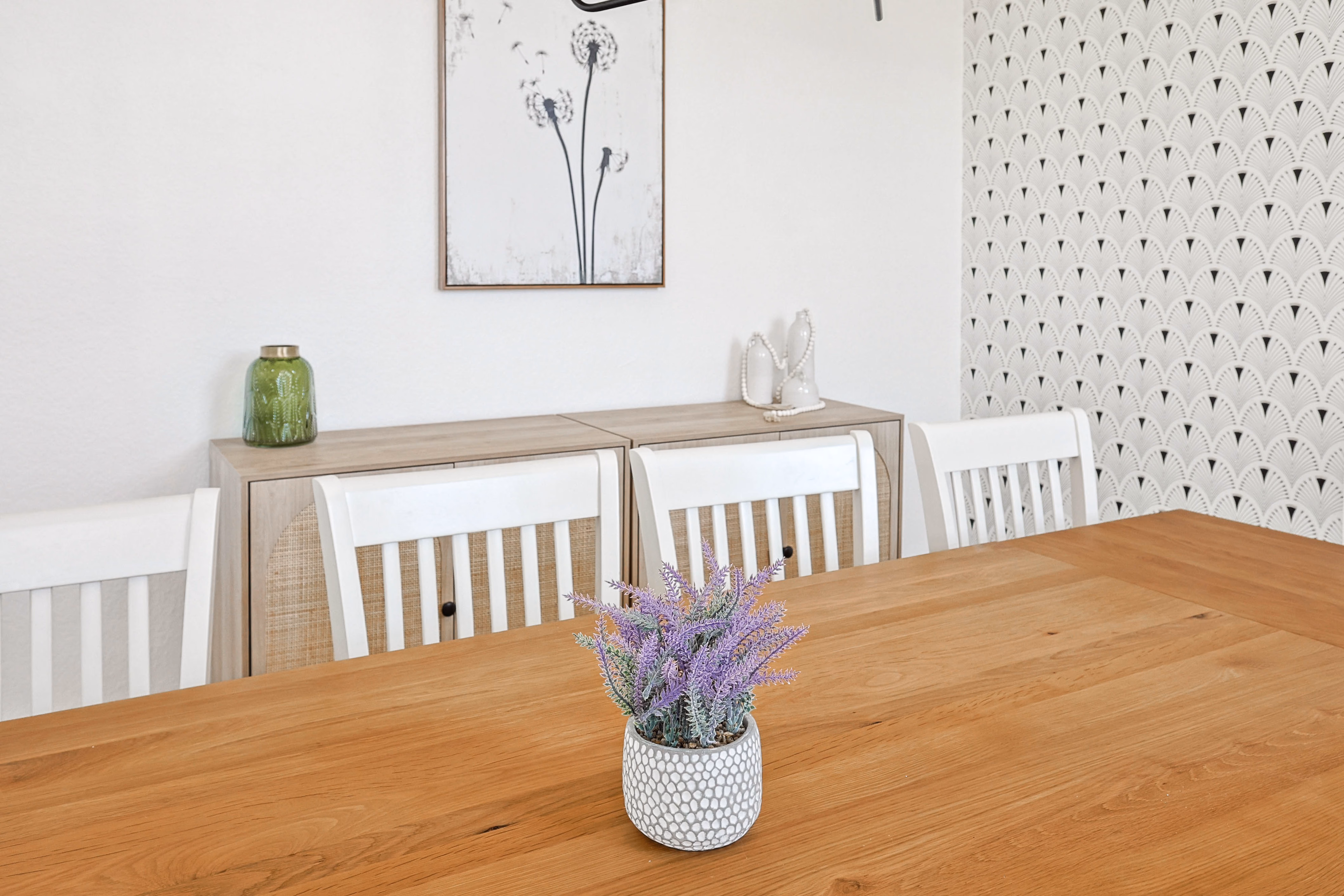 Dining room — oak farmhouse table for 10 under modern chandelier, fan-pattern accent wall.