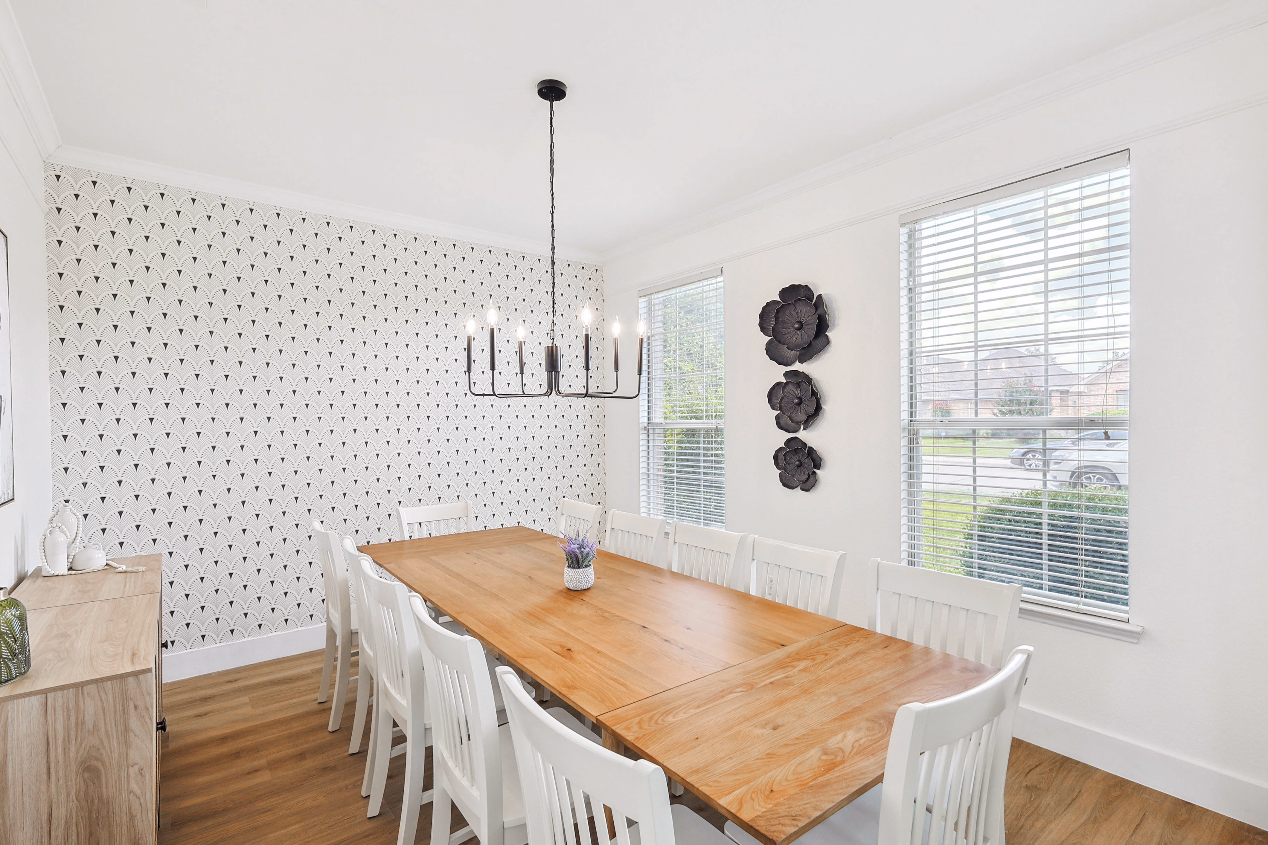 Dining room — chandelier centered, floral metal wall art beside large window.