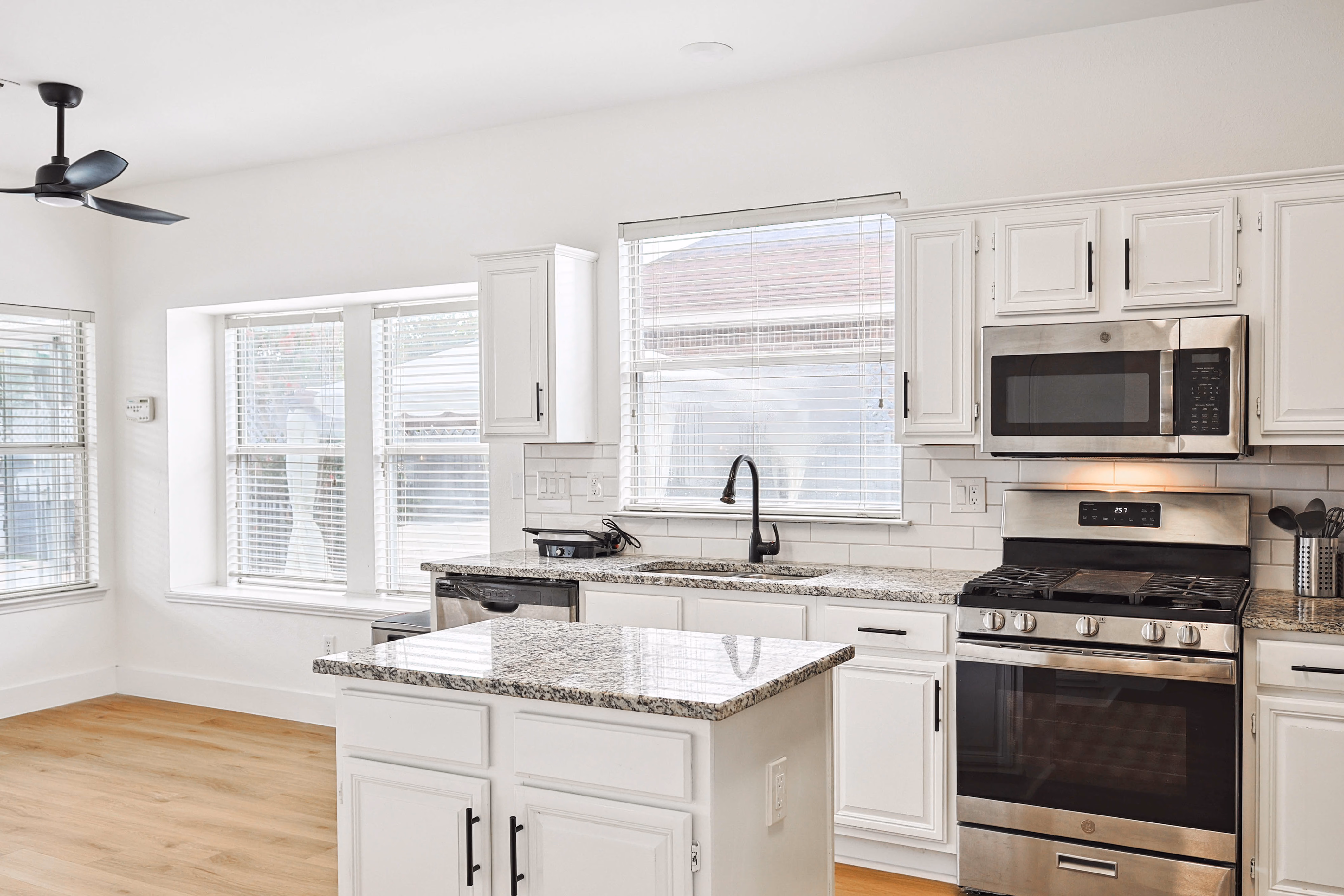 Kitchen — stainless fridge, microwave, and gas range with breakfast nook beyond.