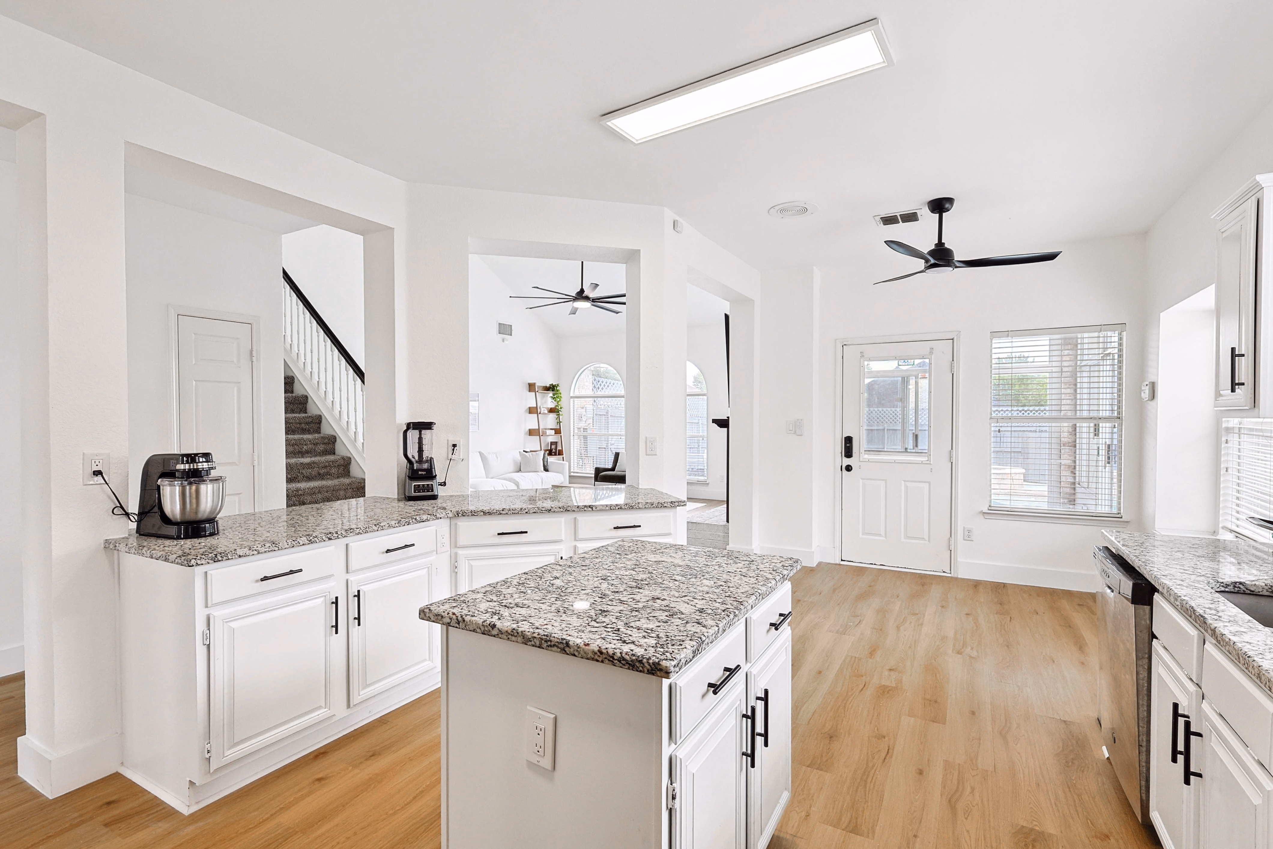 Kitchen — view across center island toward the back entry and breakfast nook with seating.