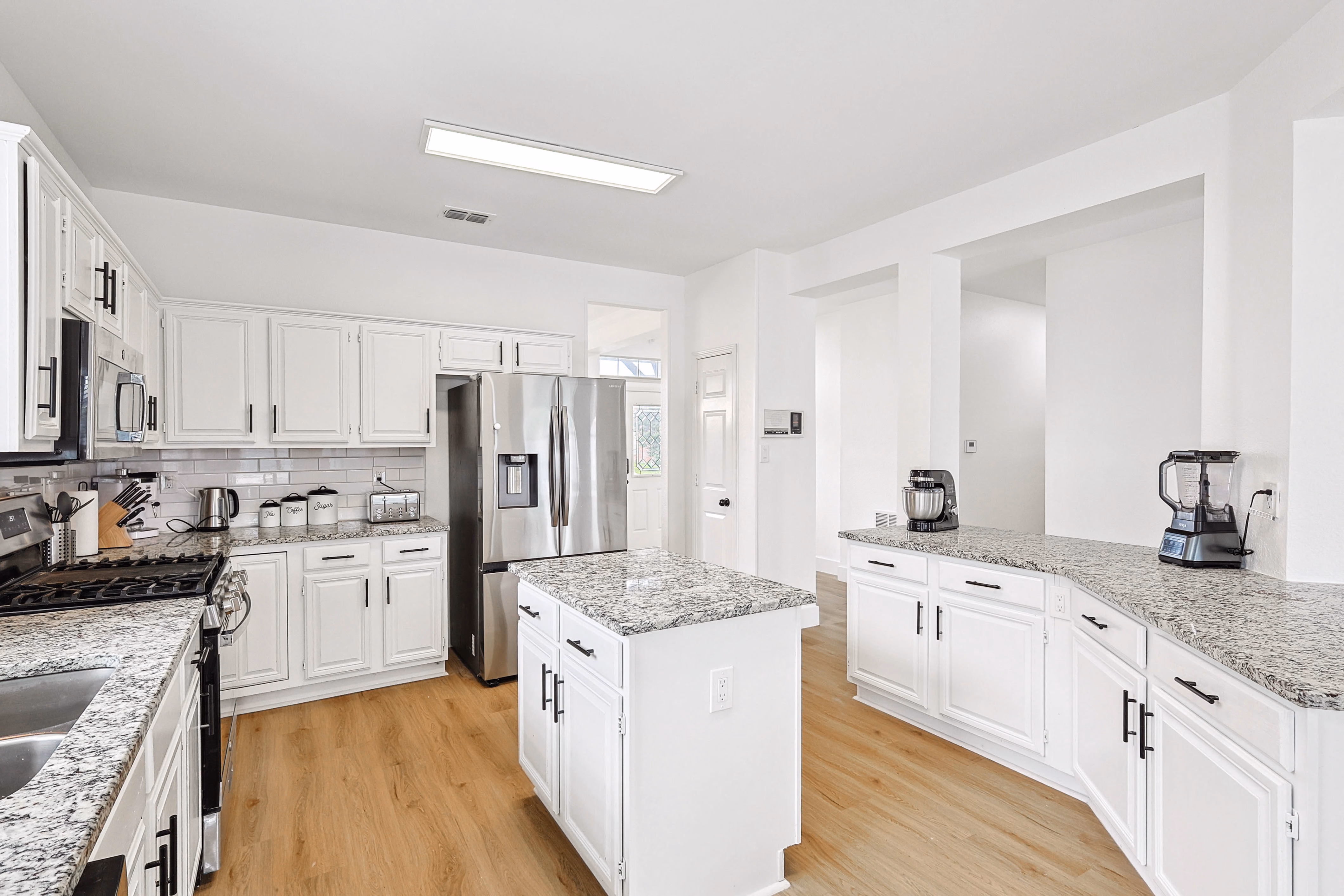 Kitchen — stainless fridge centered with prep counters, blender station, and double pendant lights.