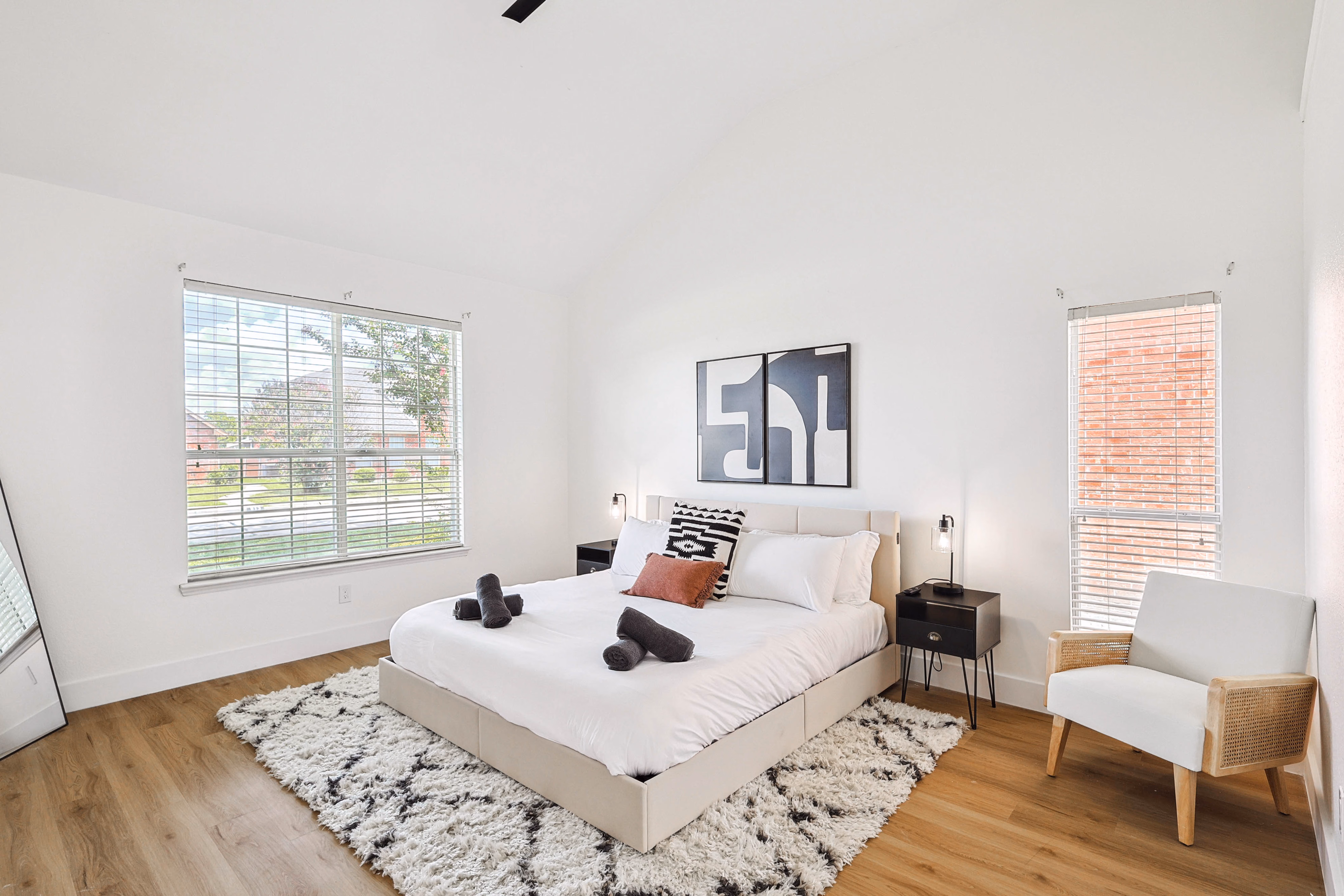 Primary bedroom — alternate angle with vaulted ceiling and large window to front yard.