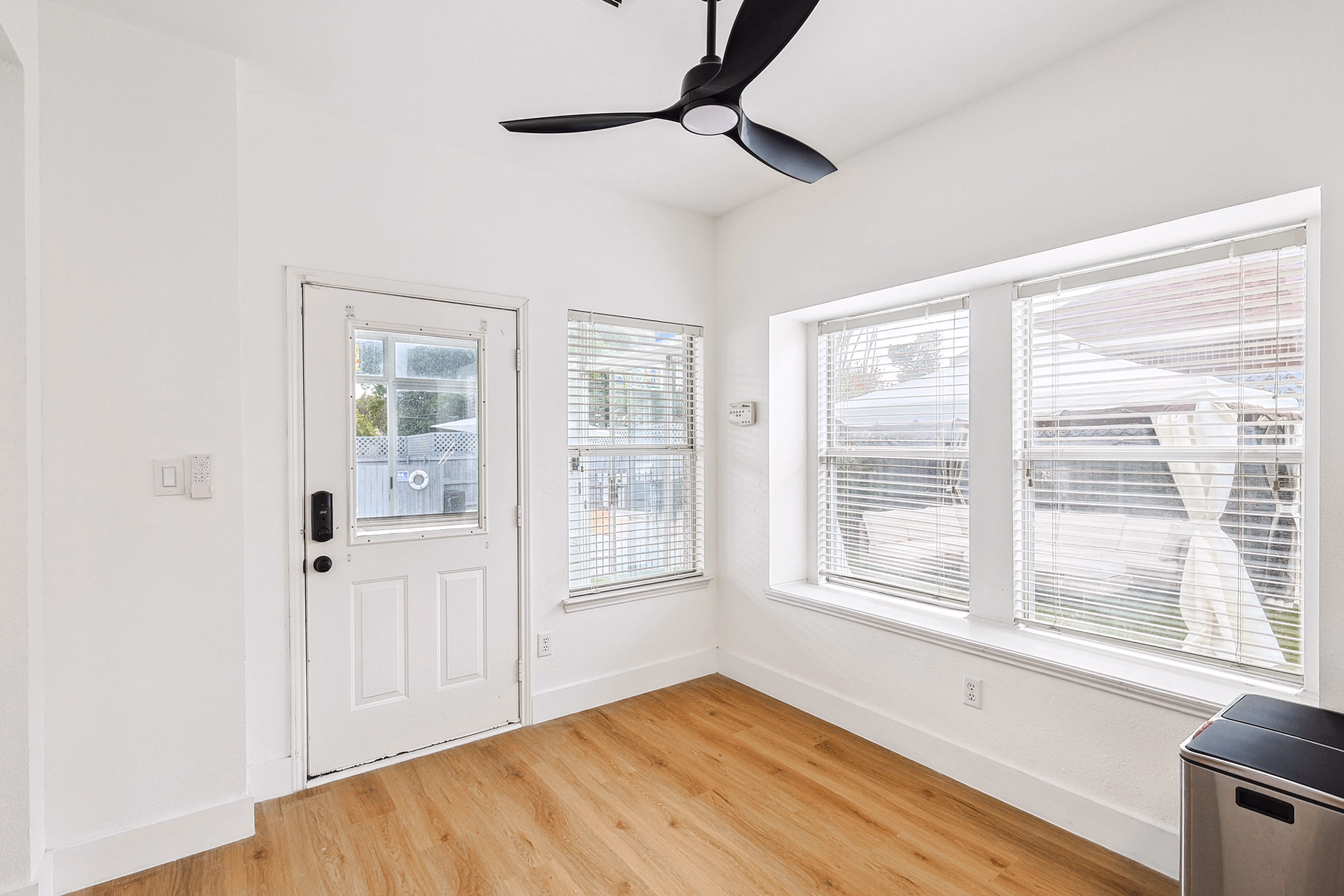 Breakfast nook / back entry — corner room with three windows, ceiling fan and back door to patio.