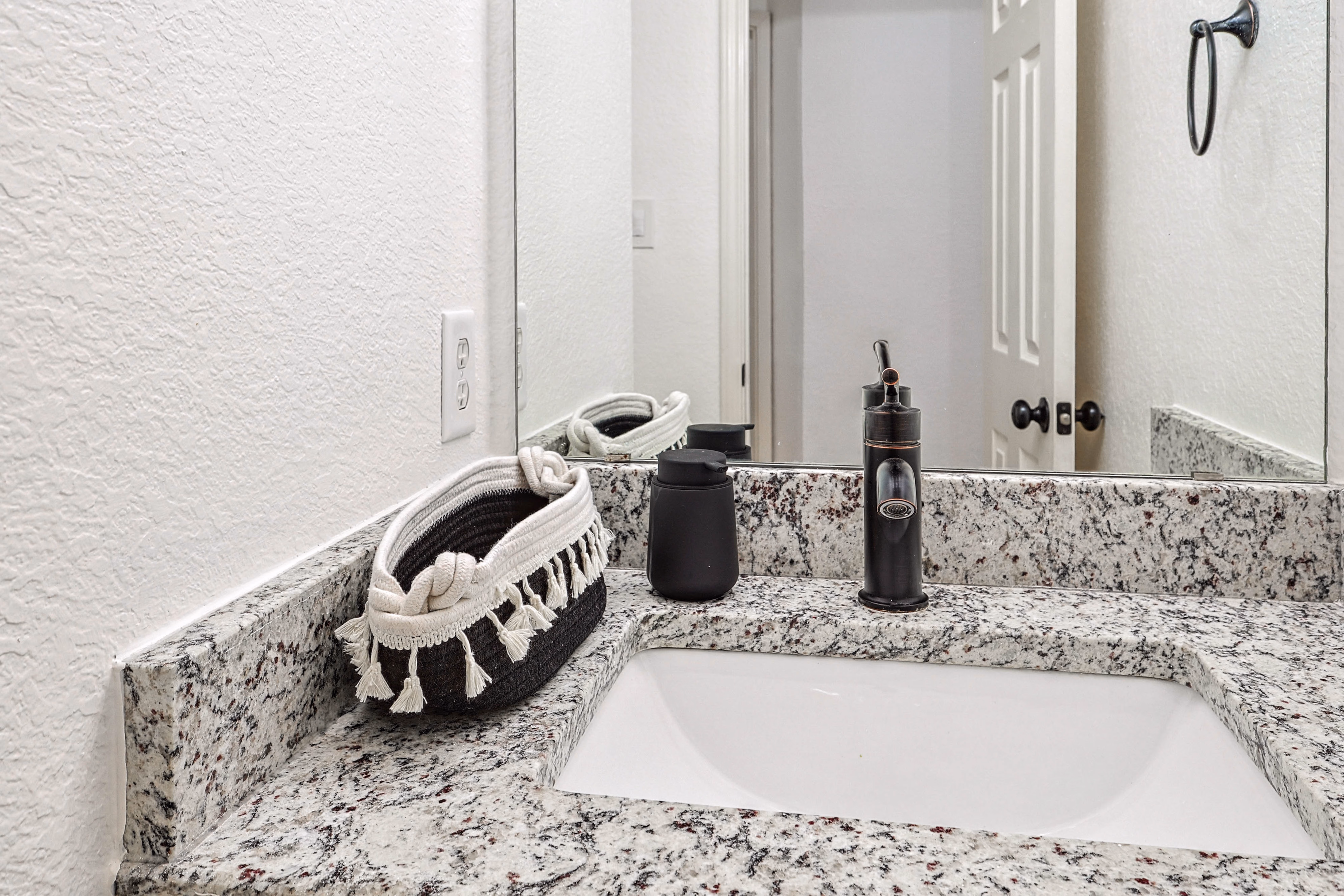 Primary bath — close-up of speckled granite vanity with mirror and shower reflection.