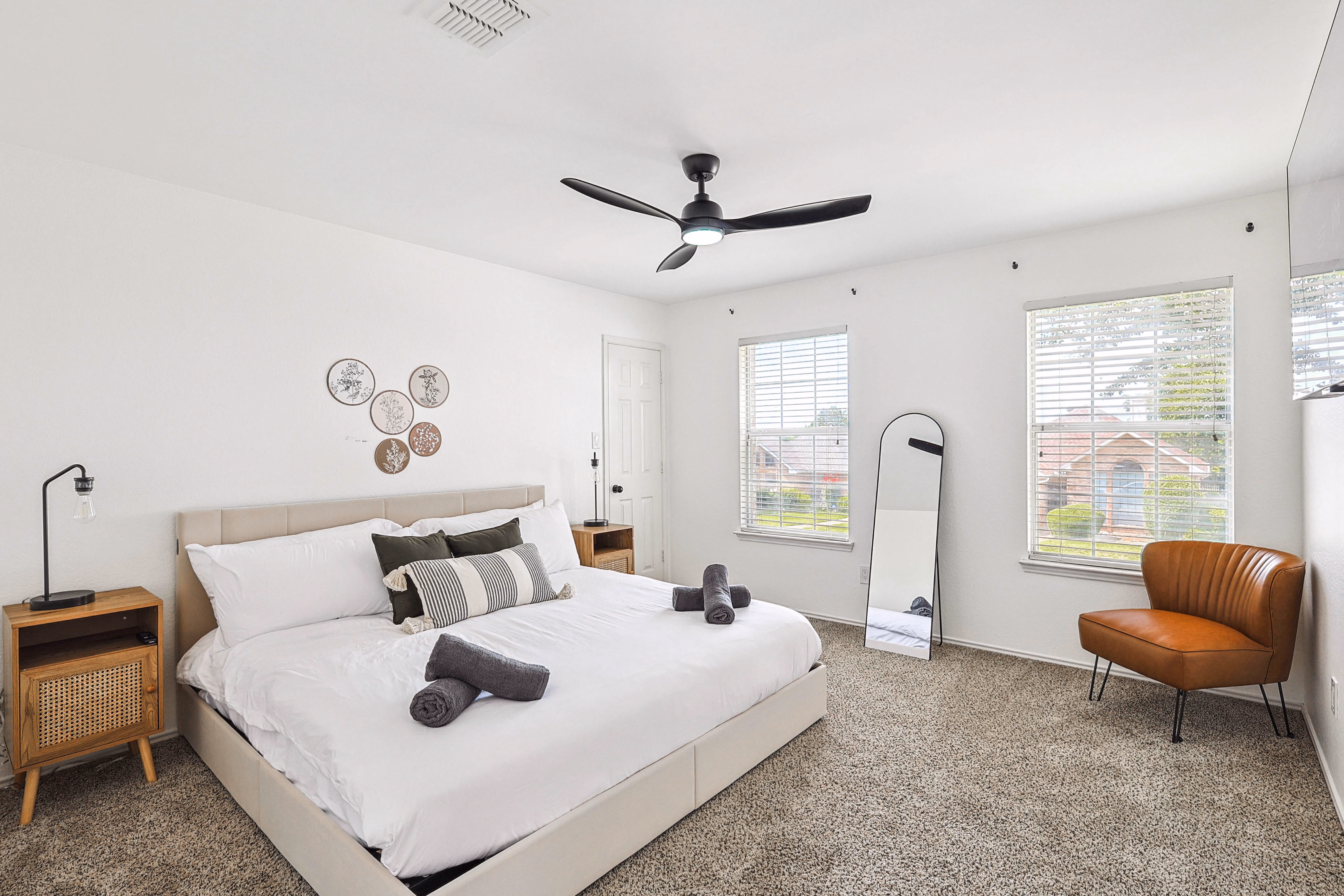 Upstairs bedroom — wider view with king bed, leather chair and two windows looking out.