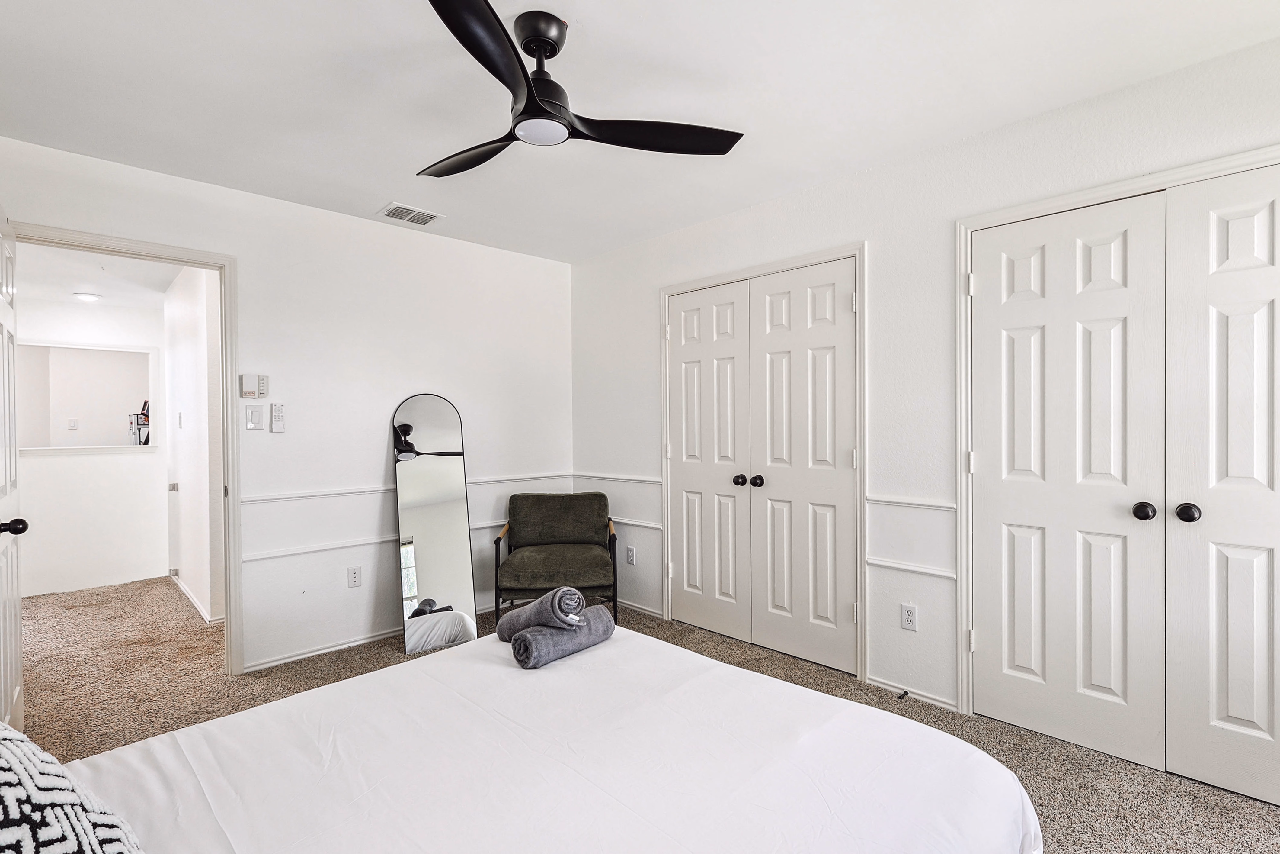 Upstairs back bedroom — two side-by-side closets with louvered doors, mirror leaning beside.