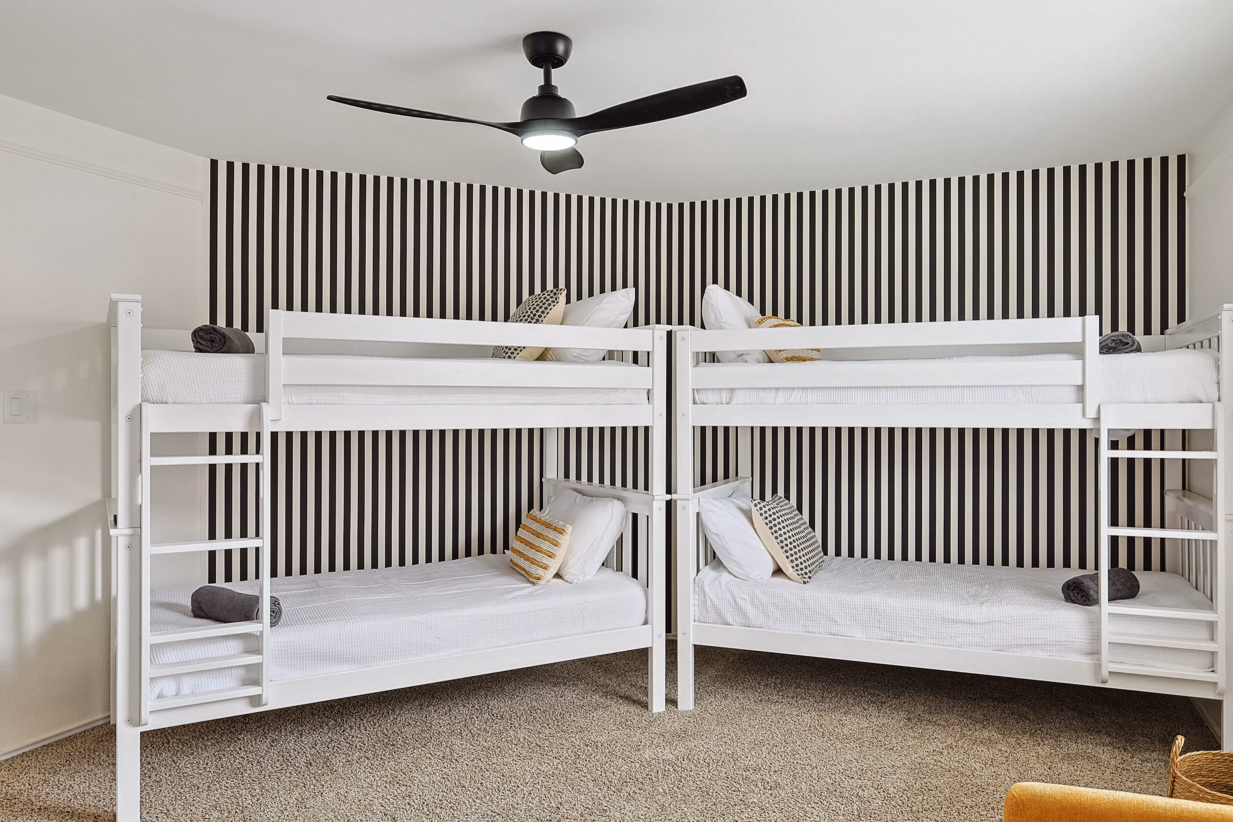 Bunk room — closer angle on the four-bunk wall against black-stripe wallpaper.