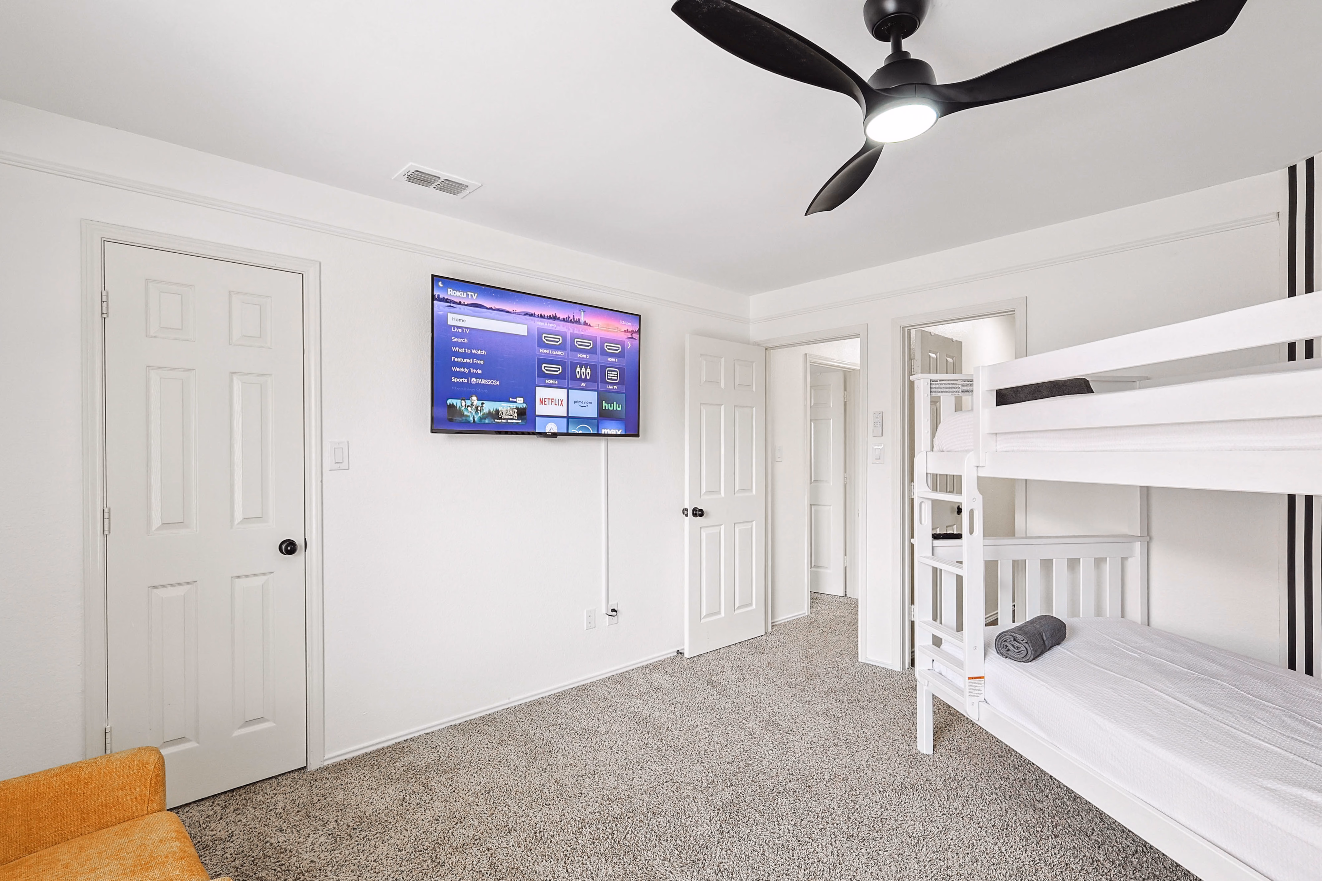 Bunk room — opposite wall with Roku TV, doorway to en-suite bath, partial bunk on right.