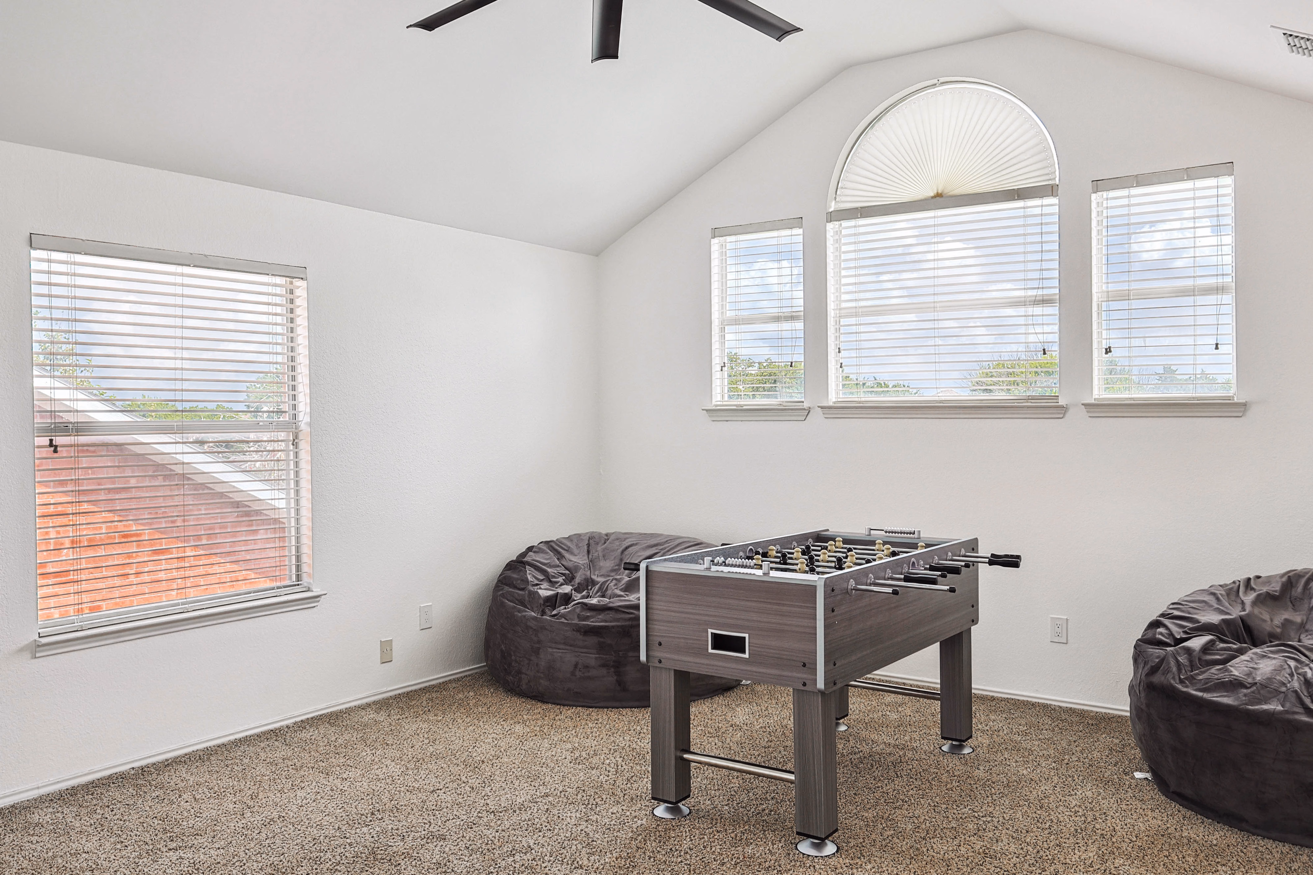 Loft game room — foosball table and bean bags under arched window wall.