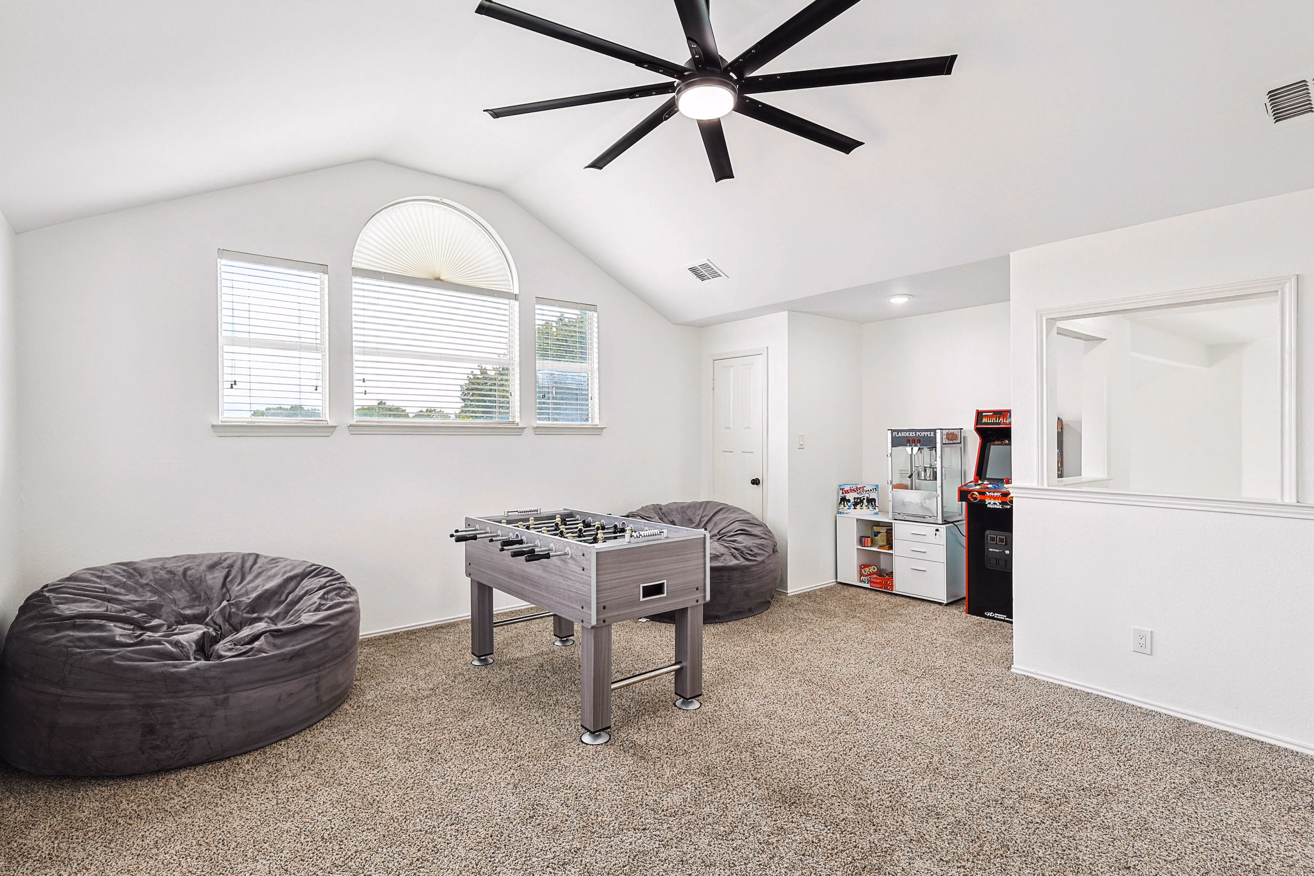 Loft game room — foosball table with bean bags, Mortal Kombat arcade cabinet and popcorn machine in corner.