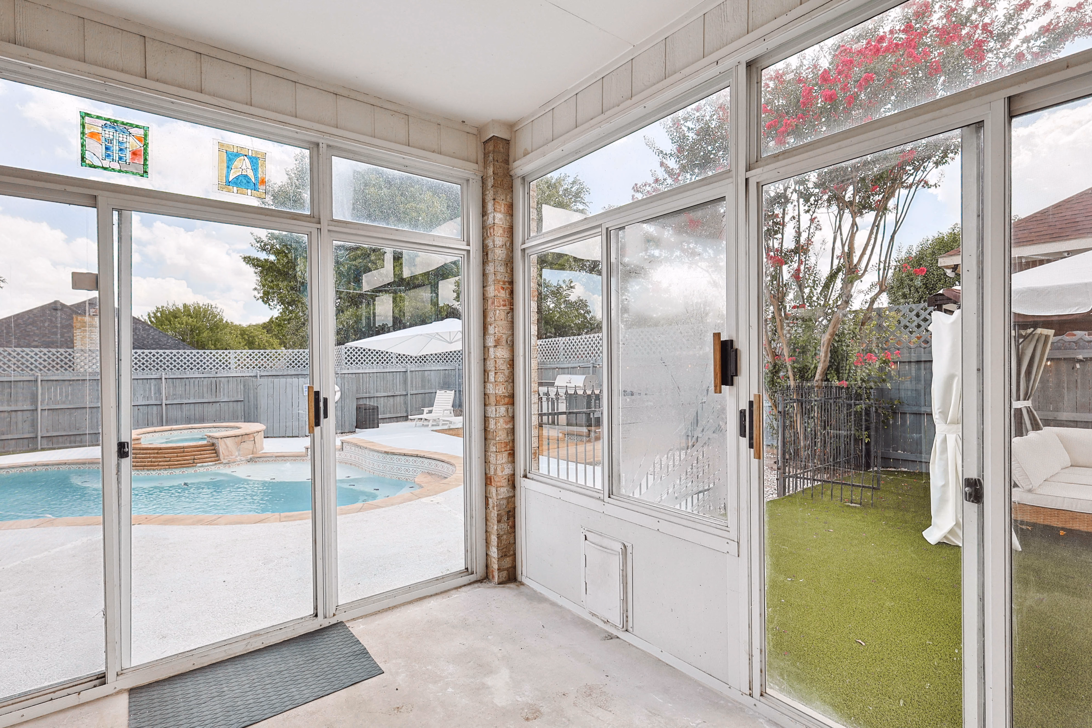 Screened porch — looking out through sliding screens to pool, hot tub and side astroturf yard.