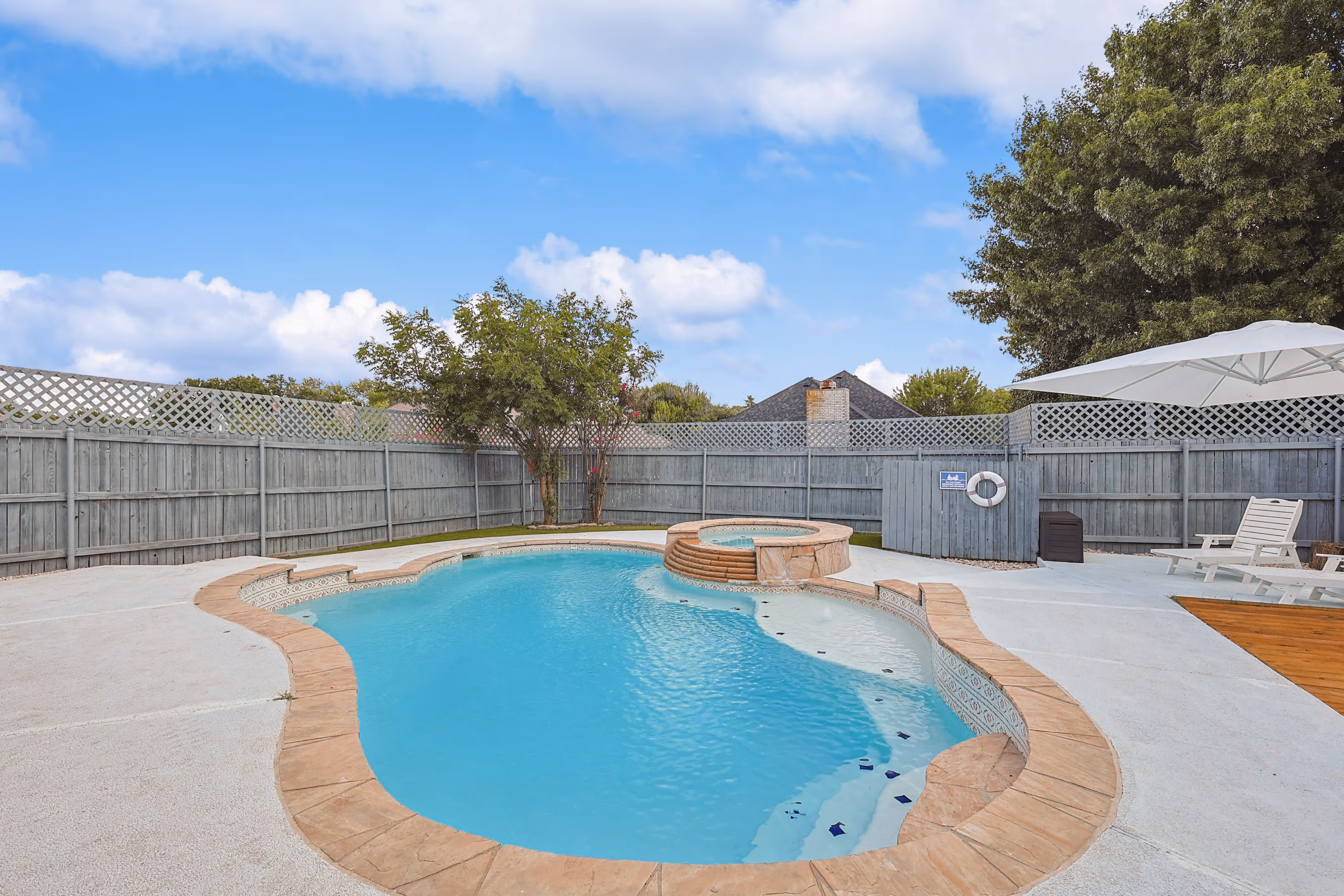 Pool — free-form in-ground pool with attached raised hot tub spa and lattice-topped fence.