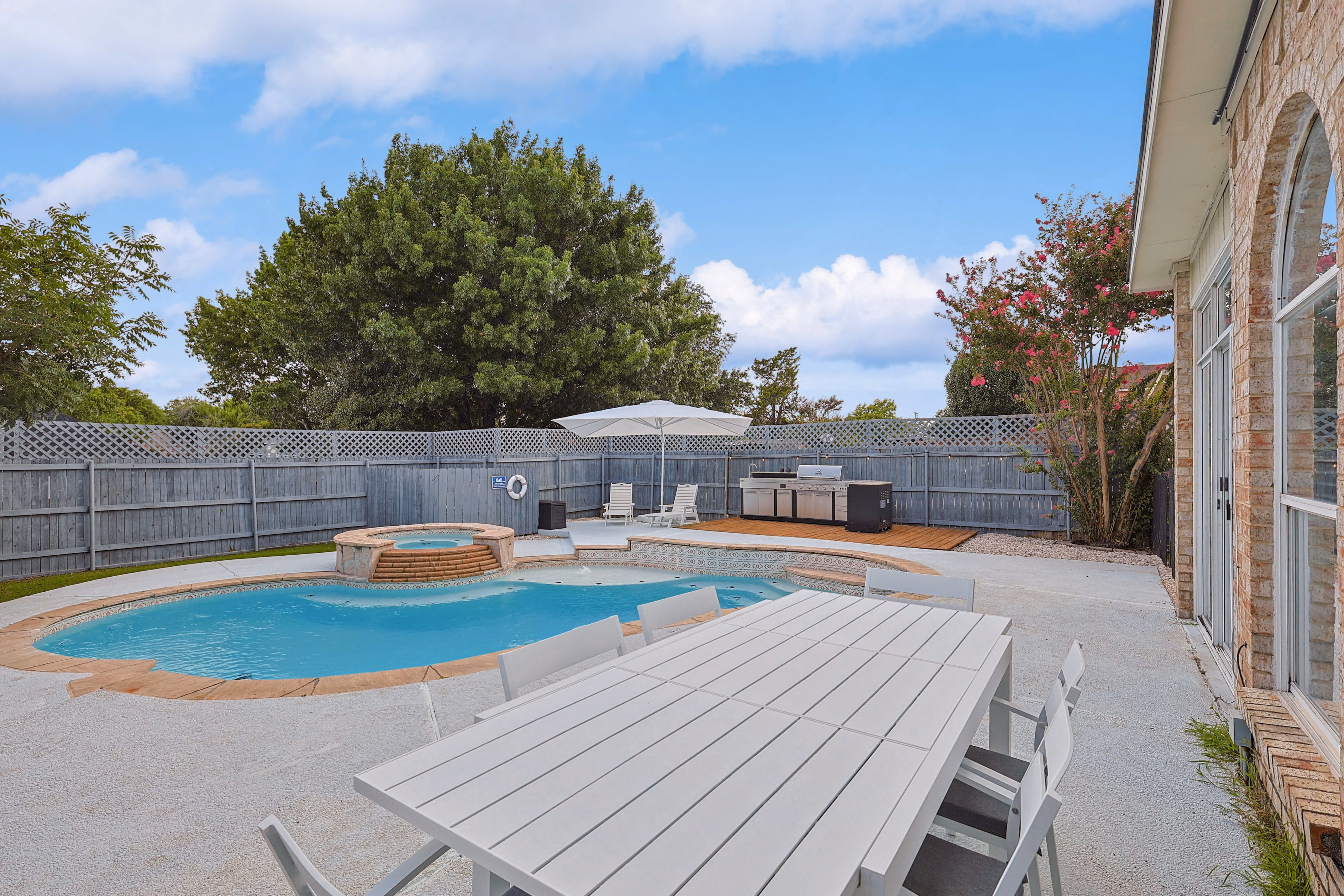 Pool and dining patio — outdoor table for six beside pool with attached hot tub spa.